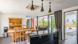 Une cuisine moderne avec un coin repas, de grandes fenêtres et une vue sur une piscine.