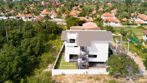 Un bâtiment moderne doté d’un toit plat, entouré d’une végétation luxuriante et offrant une vue sur la côte.