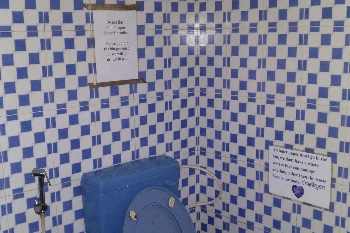 Un baño con suelo de baldosas azules y blancas formando un estampado de cuadros, un inodoro y un lavamanos.