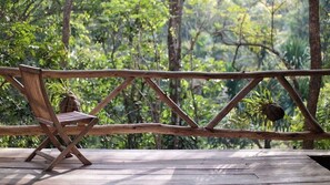 A wooden deck with a bench and a rope barrier overlooking a forested area.