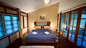 Un dormitorio con una cama grande, vistas a través de las ventanas y una lámpara en el techo.