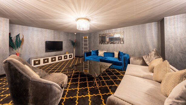 A modern living room with a large flat-screen TV, a blue sofa, and a patterned carpet. - 216 Macity (Istanbul)
