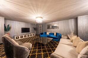 Un salon moderne avec un grand téléviseur à écran plat, un canapé bleu et un tapis à motifs.