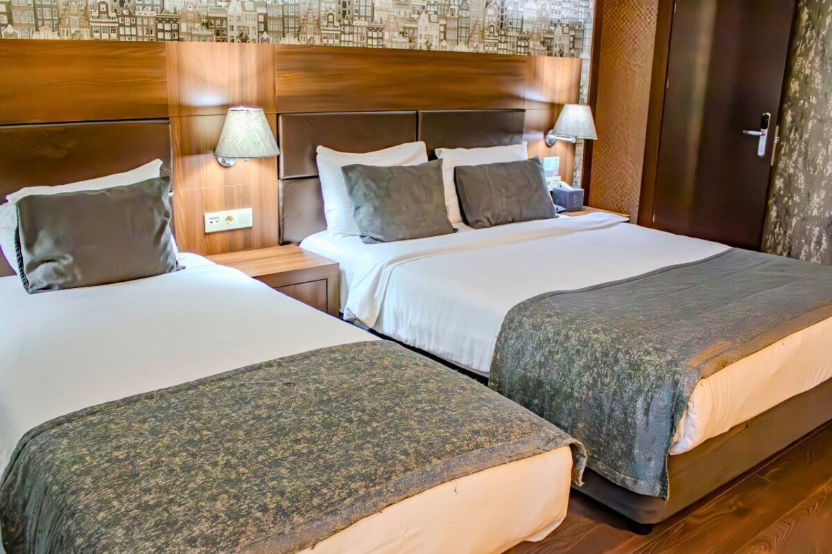 A hotel room with two beds, wooden headboards, and a patterned wall.