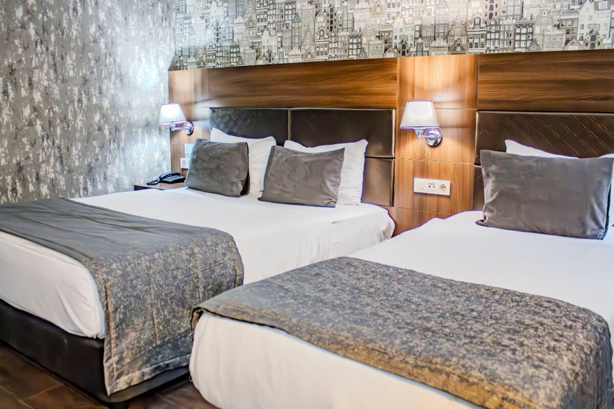 A hotel room with two beds, a textured wall, and a cityscape wallpaper.