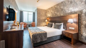 A hotel room with a large bed, bedside tables, a desk with a chair, a TV, and a patterned wallpaper. - 216 Macity (Istanbul)