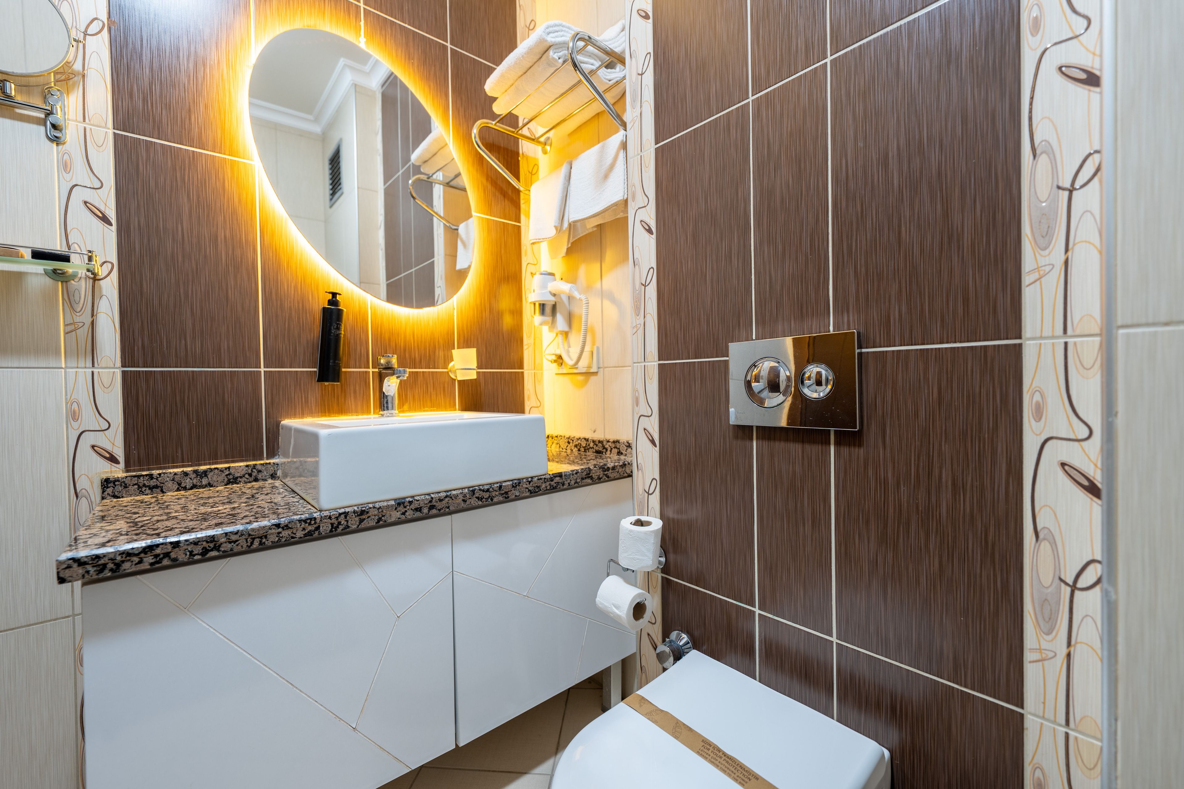 A modern bathroom with a vanity, sink, mirror, towel rack, and toilet.