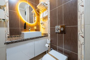 Un bagno moderno con lavabo, specchio, portasciuga e servizi igienici.