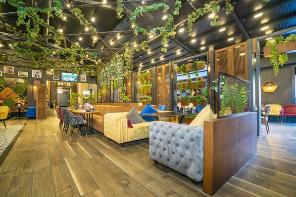 Relax in our inviting lobby, featuring plush sofas, a reception desk, and lush greenery.