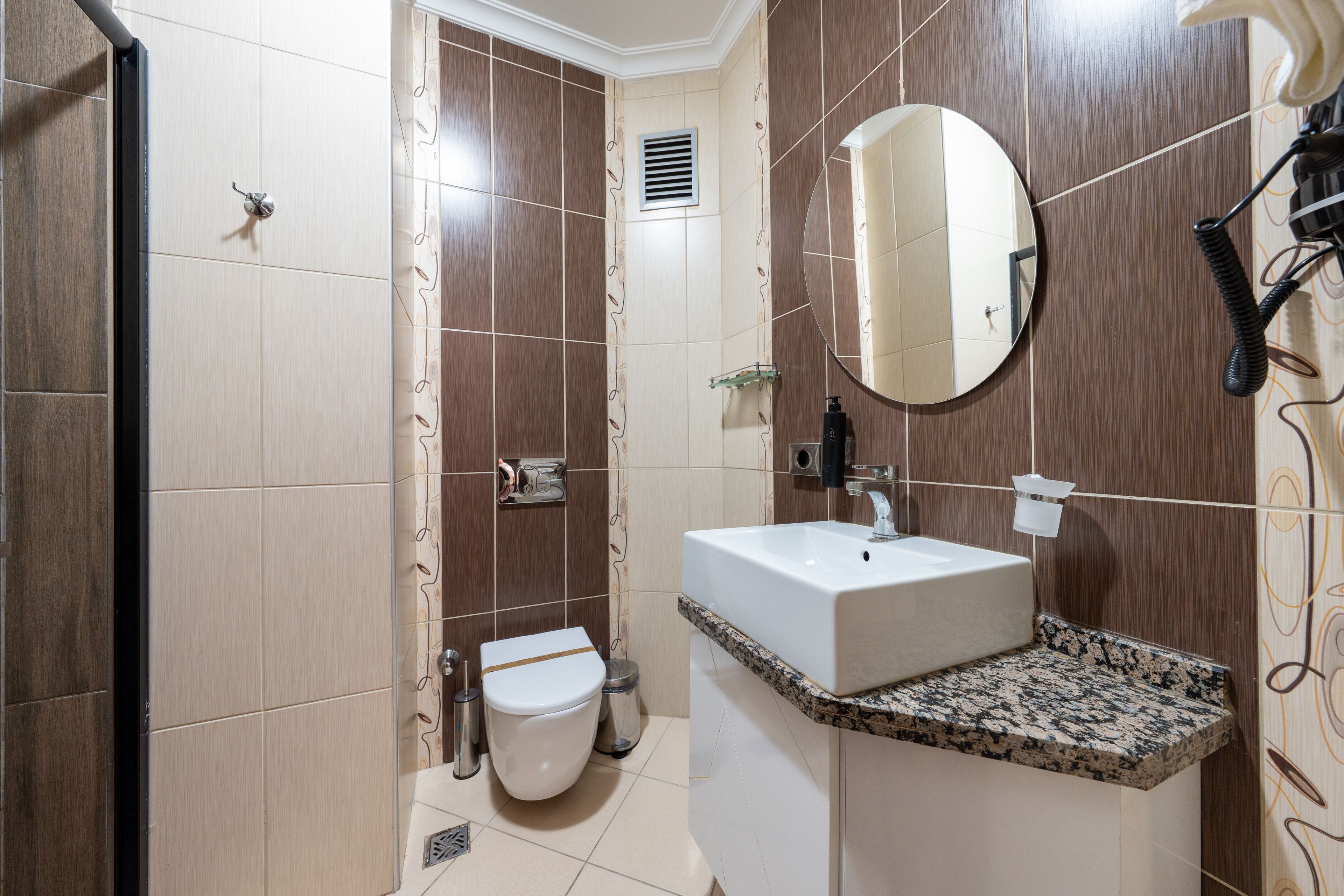 Ein Badezimmer mit einem weißen Waschbecken, einem Spiegel und einer Toilette.