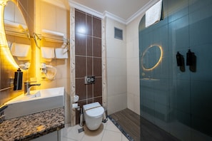 A bathroom with a sink, mirror, towel rack, toilet, and a glass shower enclosure. - 216 Macity  (Istanbul)