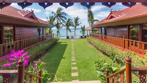 A pathway leading to a pool area with a view of the sea, surrounded by palm trees and a tropical garden. - 5BR Beachfront Villa Bangrak (Koh Samui)