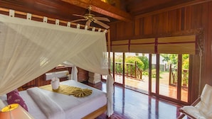 A room with a bed, a ceiling fan, a chair, and a view of the outdoors. - 5BR Beachfront Villa Bangrak (Koh Samui)