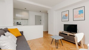 A modern living room with a grey sofa, a small table, and a TV. There are two framed artworks on the wall. - ShortStayPoland Jana Pawła - B27 (Warsaw)
