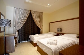 Une chambre d’hôtel avec deux lits simples, un bureau avec une chaise et une lampe.