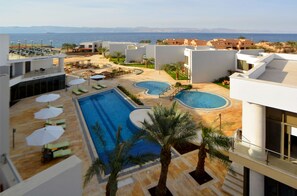 A resort with a swimming pool, lounge chairs, and a view of the sea. - Public Security Hotel & Chalets (Aqaba)