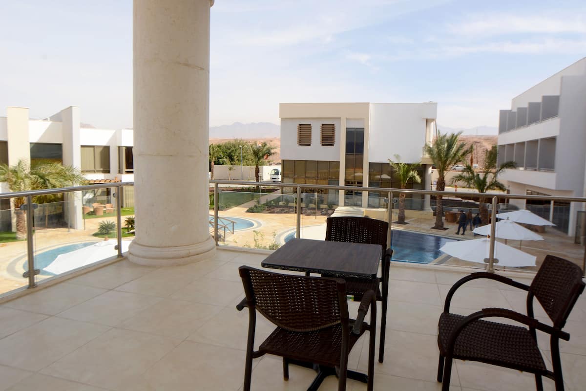 A balcony with a pool, chairs, and a view of a desert landscape.