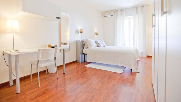 A hotel room with a bed, a desk, a chair, a mirror, and two bedside lamps. - Rooms Rent Vesuvio B&B (Naples)