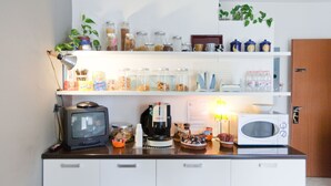 A kitchen with a microwave, coffee maker, and various jars on shelves. - Rooms Rent Vesuvio B&B (Naples)