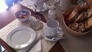 A dining table set with plates, cups, a pitcher, a bowl of snacks, and a basket of pretzels. - Rooms Rent Vesuvio B&B (Naples)
