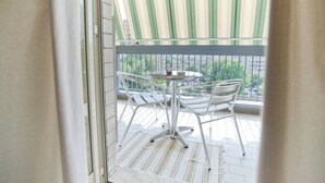 A balcony with a striped awning, a round table, and two chairs. - Rooms Rent Vesuvio B&B (Naples)