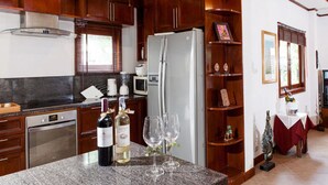 Una cocina con encimeras de granito, un refrigerador de acero inoxidable y armarios de madera.