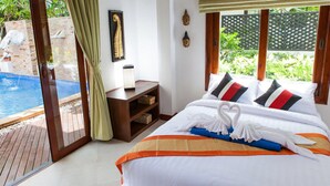 Habitación de hotel con cama, mesita de noche, ventana con vista a una piscina y follaje, y piso de madera.