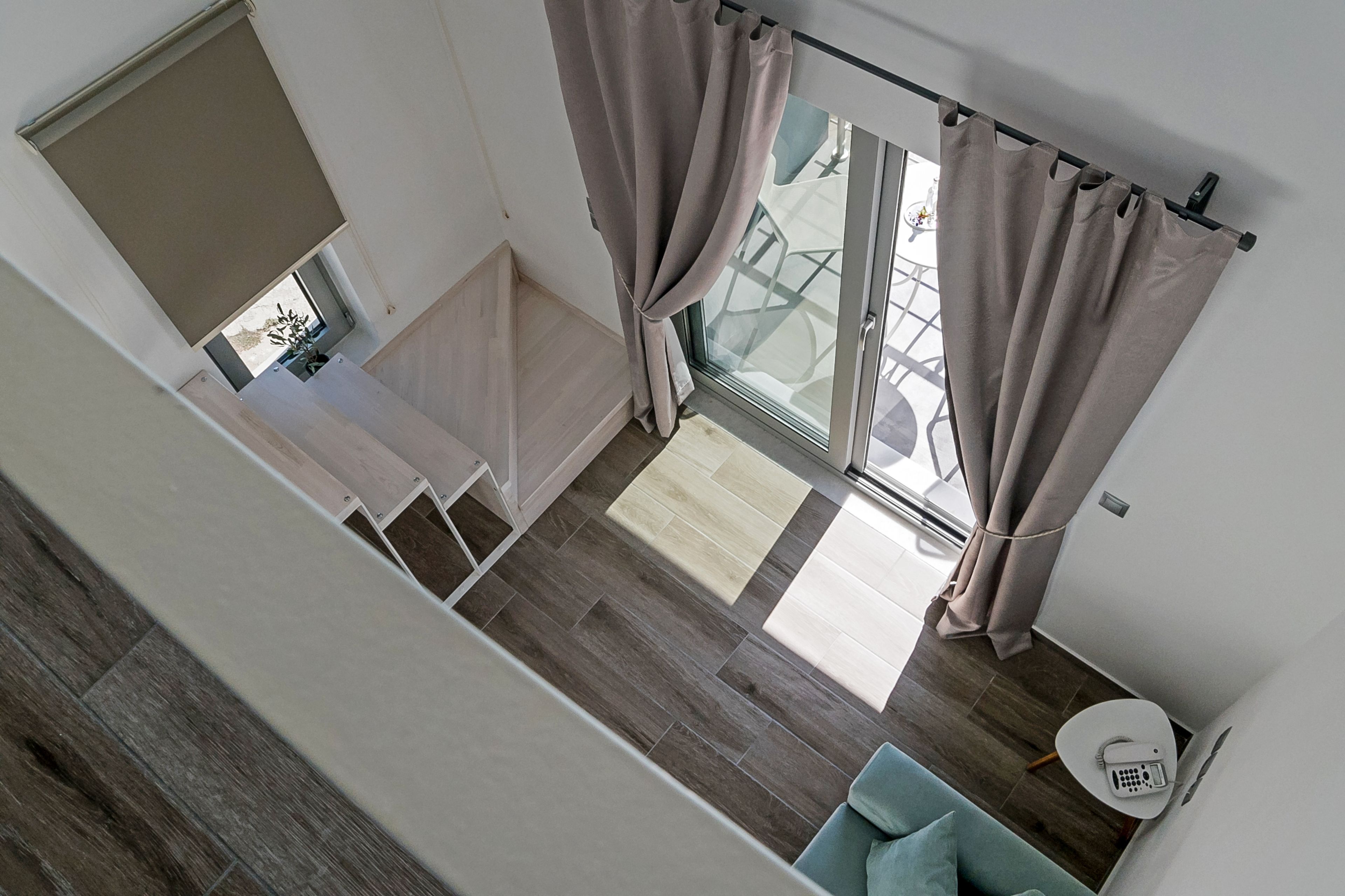 Un interior moderno con una escalera, un comedor con mesa de vidrio y vistas al exterior.
