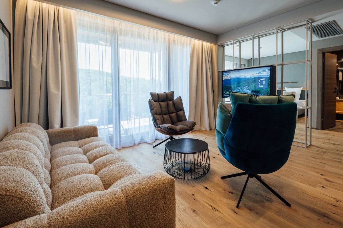 A modern living room with a sofa, armchair, and a TV.