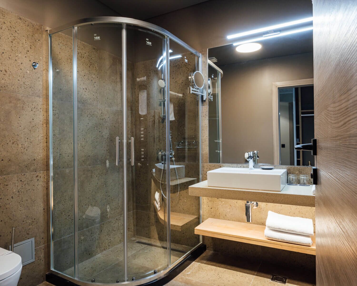 Une salle de bain moderne avec une douche à parois de verre, un lavabo blanc et un meuble-lavabo en bois.