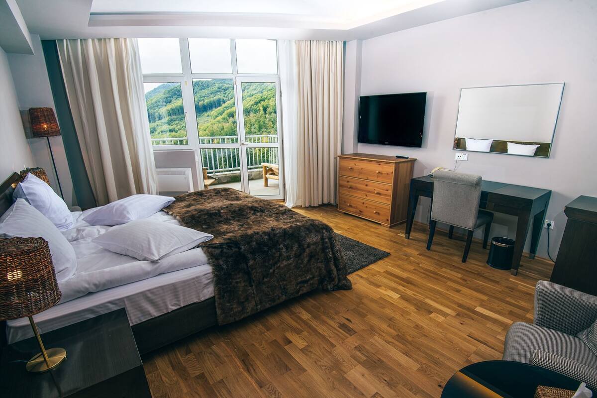 A bedroom with a bed, a TV, a dresser, a desk, and a chair.