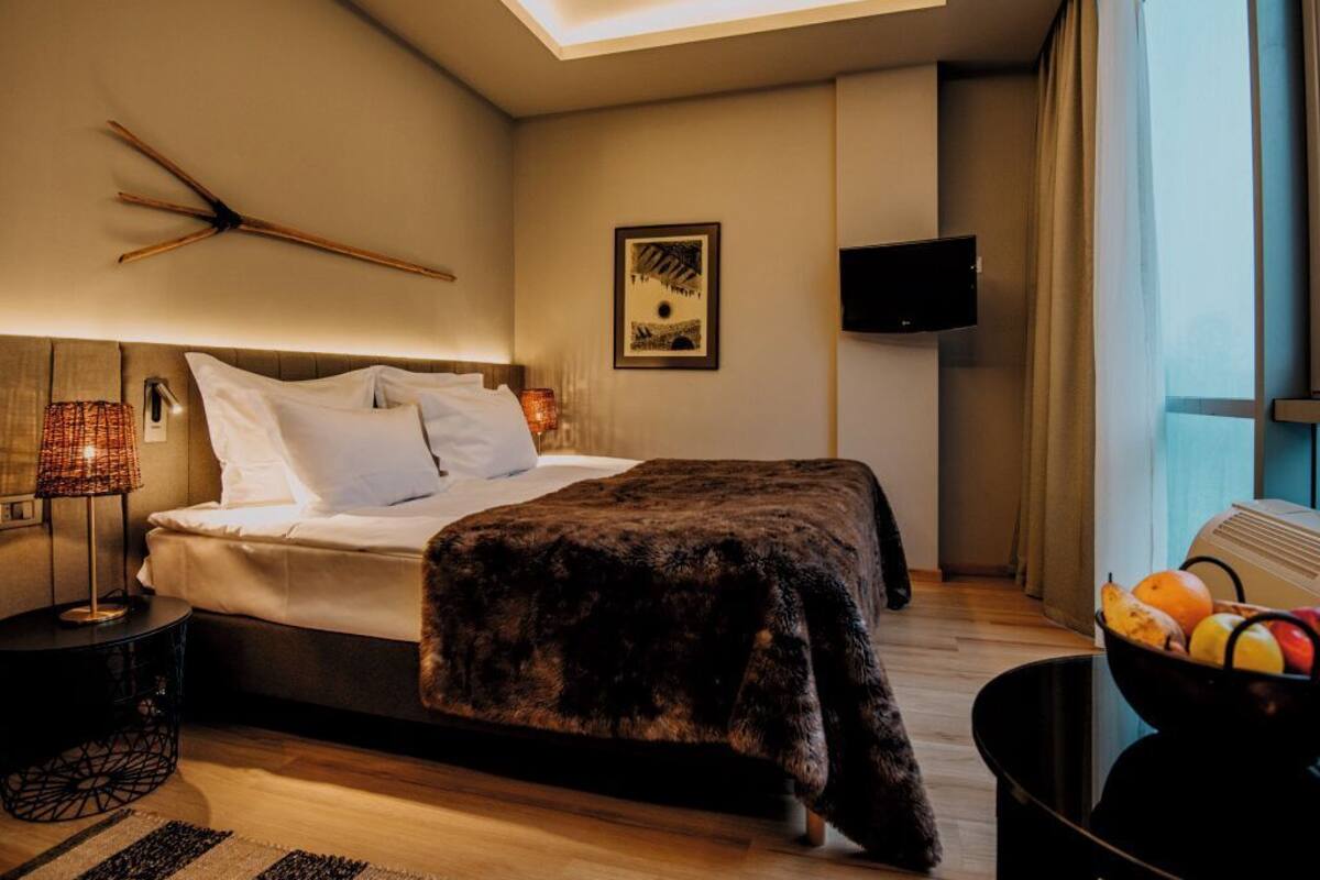 A modern bedroom with a bed, bedside lamp, and a TV.