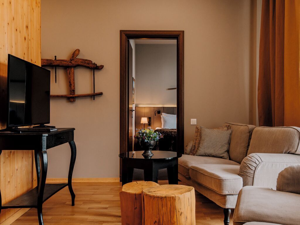 En hyggelig stue med et fjernsyn på et træbord, en sofa og et lille bord med en plante.