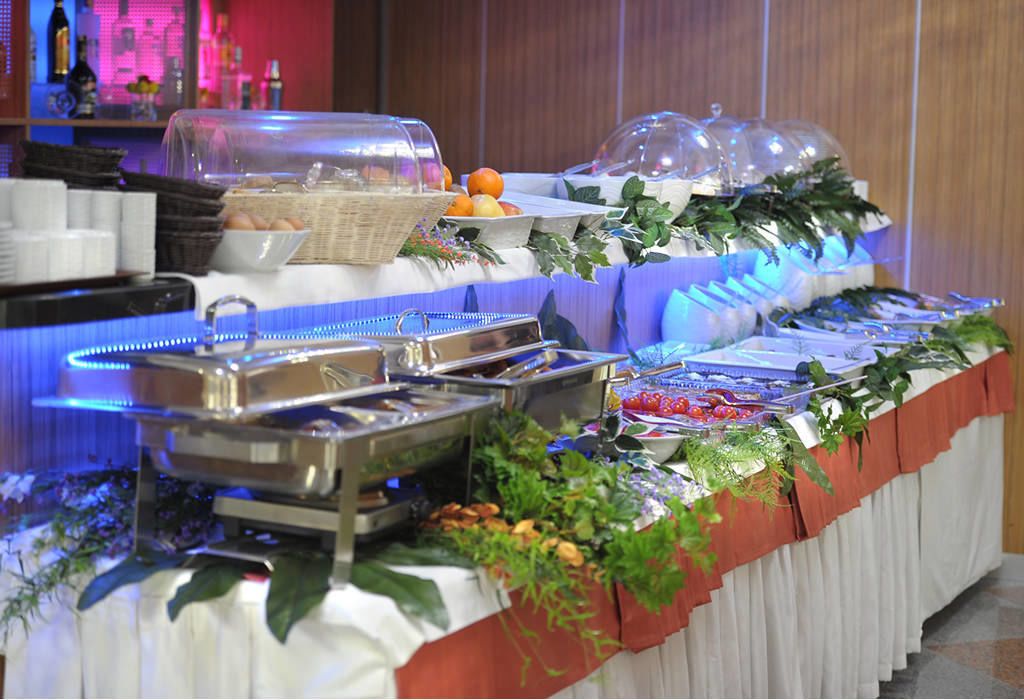 A buffet setup with various food items and a decorative plant arrangement.