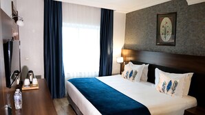A hotel room with a bed, a desk with a lamp, a water bottle, and a framed picture on the wall. - Rhiss Hotel Bostanci (Istanbul)