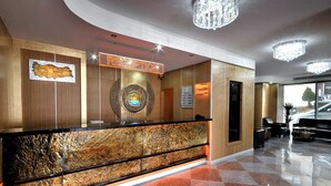 A reception area with a wooden reception desk, a reception sign, a chandelier, and a checkered floor. - Rhiss Hotel Bostanci (Istanbul)