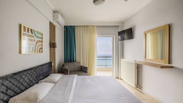 Ein Hotelzimmer mit Bett, Stuhl, Fernseher und Meerblick.