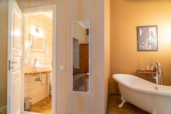 A bathroom with a bathtub, a sink, and a mirror. - Godart Rooms (Tallinn)