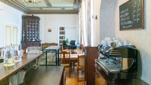 Interior de una cafetería con barra, máquina de espresso y menú en pizarra.