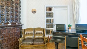 Una habitación con un sofá de cuero marrón, un armario de madera, una estantería y un piano negro.