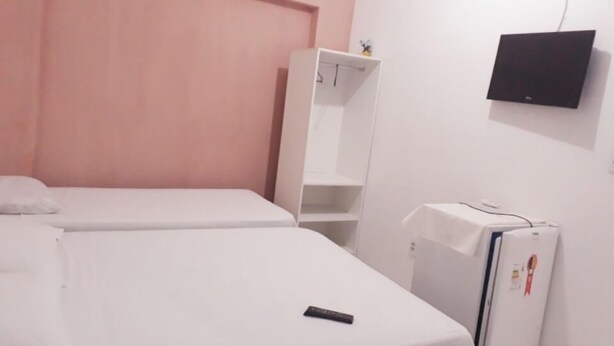 A room with two beds, a wardrobe, a TV, and a refrigerator. - Pousada do Castelo (Fortaleza)