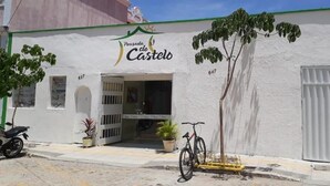 A building with a sign reading "Pousada do Castelo" and a bicycle parked in front. - Pousada do Castelo (Fortaleza)