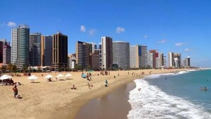 A beach with a row of high-rise buildings in the background. - Pousada do Castelo (Fortaleza)