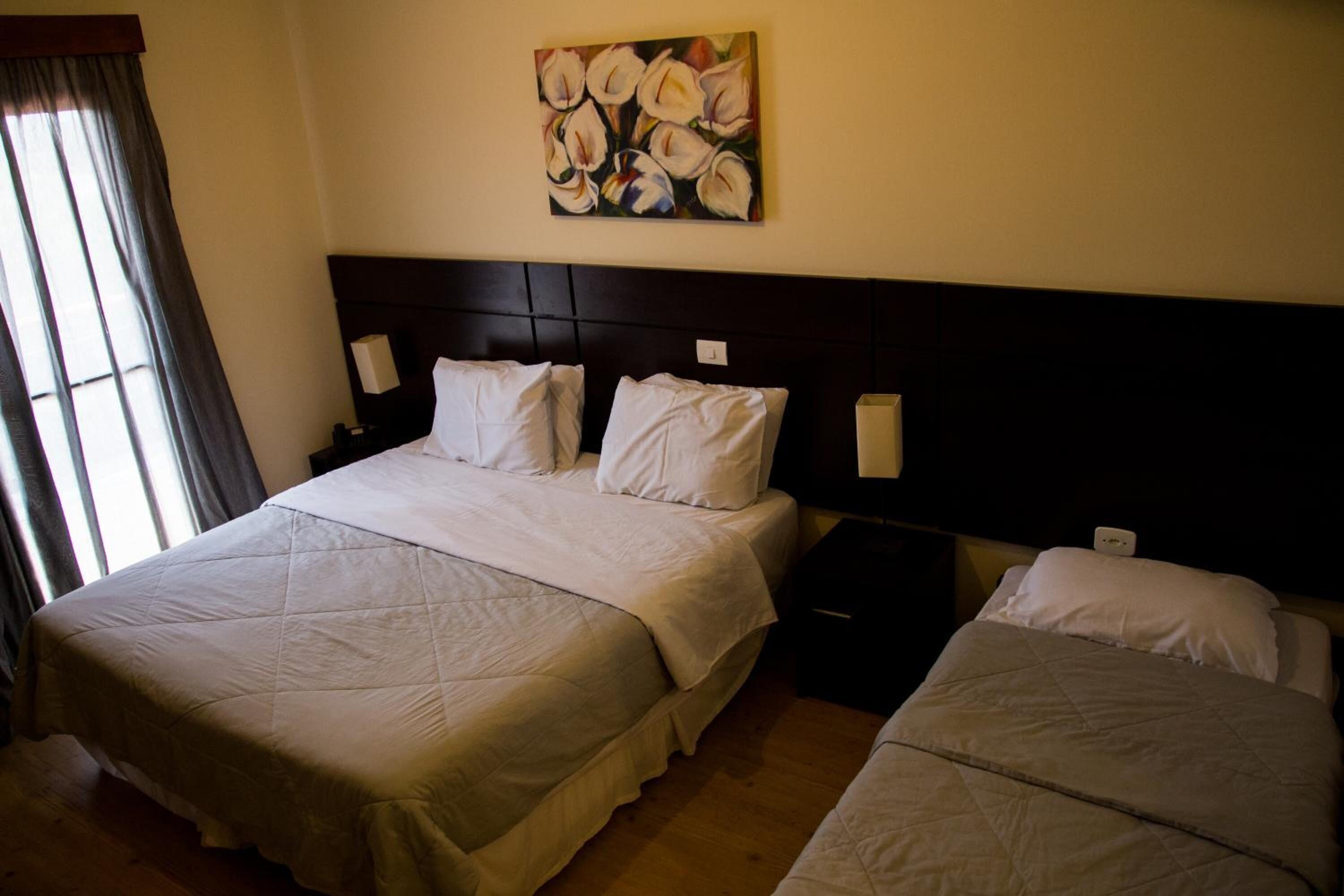 A hotel room with two beds, a dark headboard, and a painting on the wall.