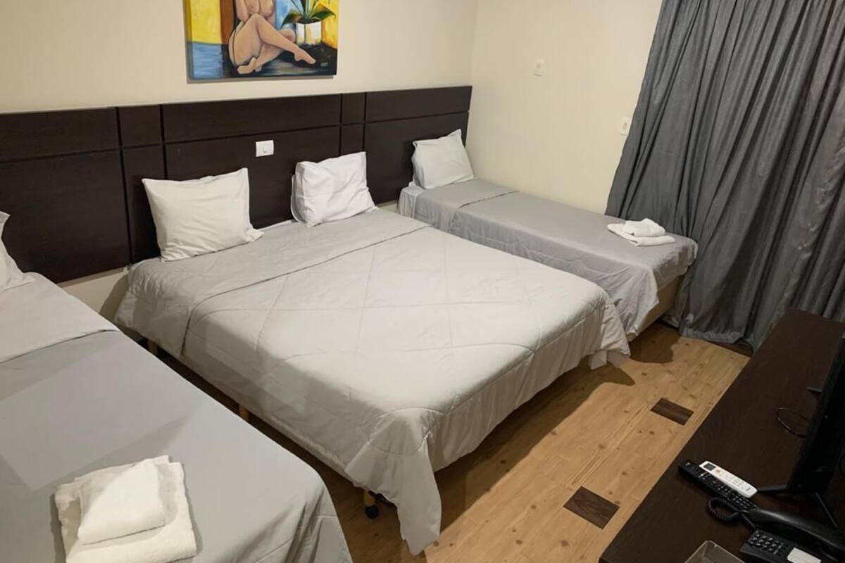 A hotel room with two beds, a desk with a computer, and a painting on the wall.