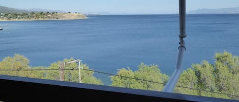 Vista desde un balcón sobre una extensa masa de agua, con una costa distante y algo de vegetación.