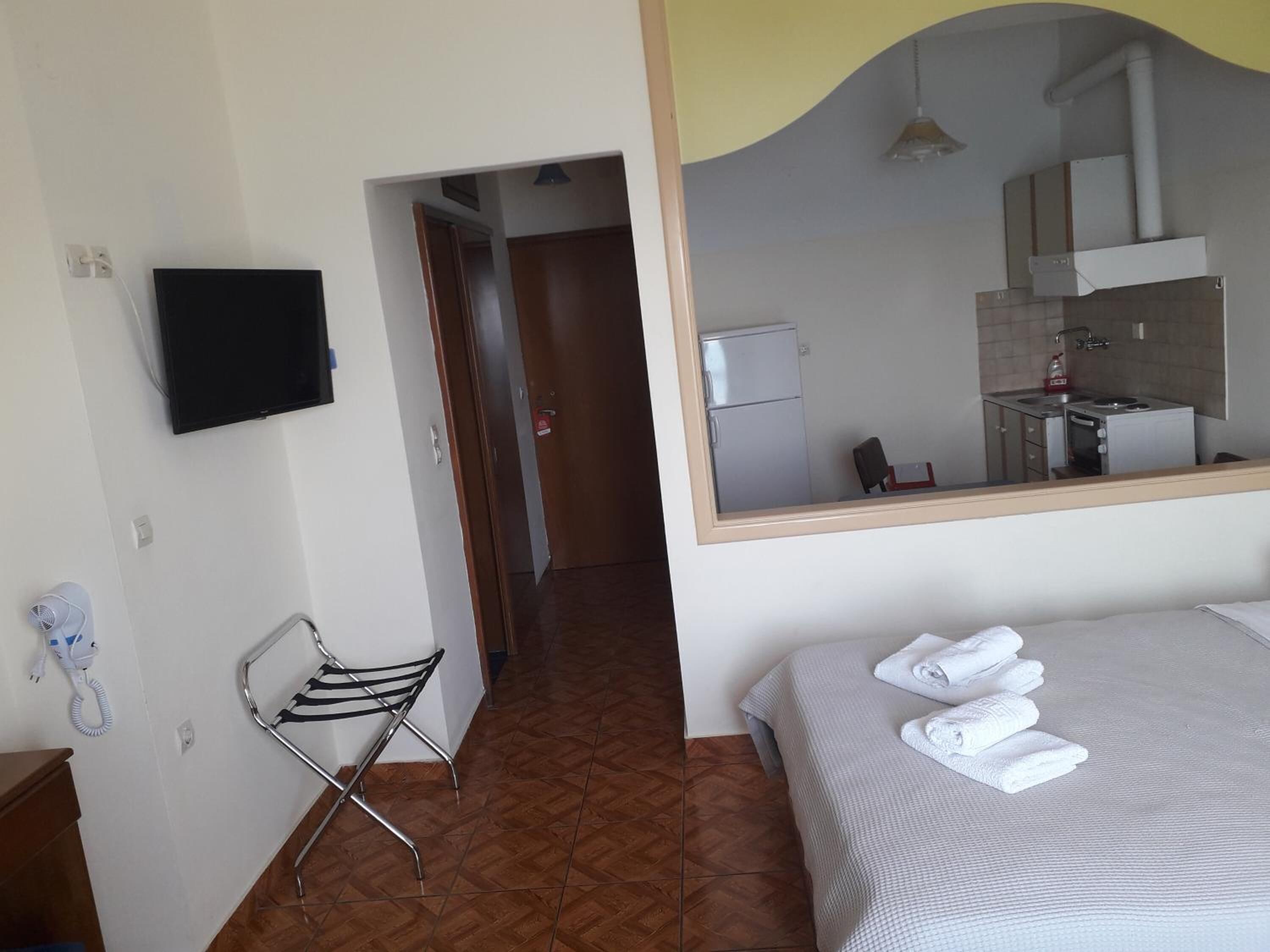 Habitación de hotel con una cama, un espejo que refleja una cocina, una silla y un teléfono.