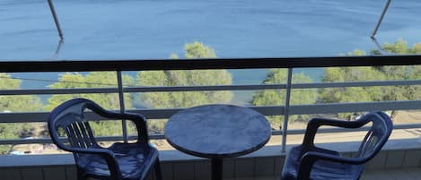 A balcony with a table and chairs overlooking a body of water and distant land.
