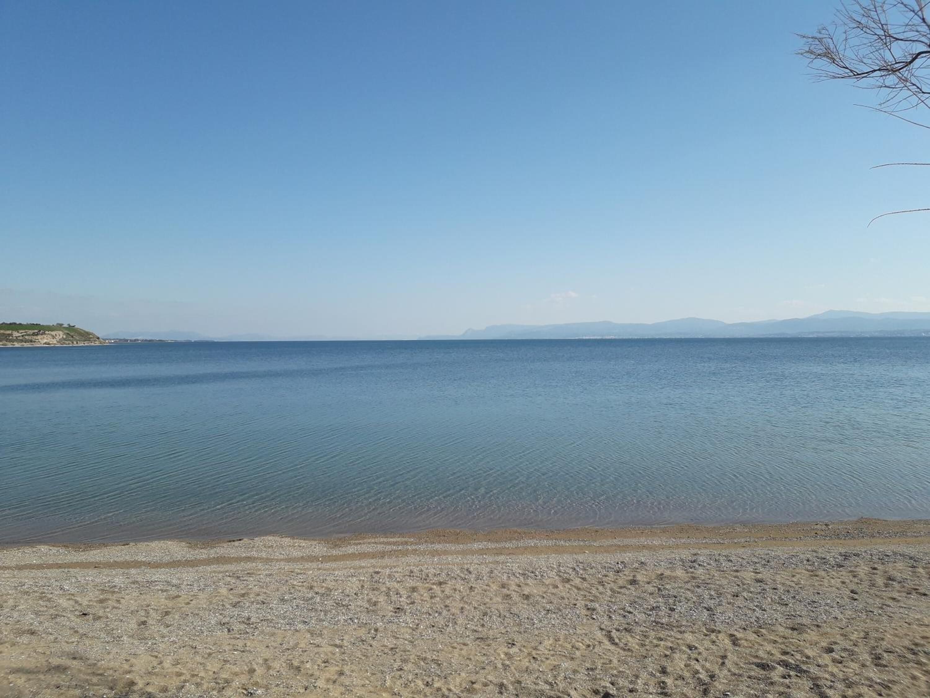 Une mer calme, une plage de sable et des montagnes à l’horizon.