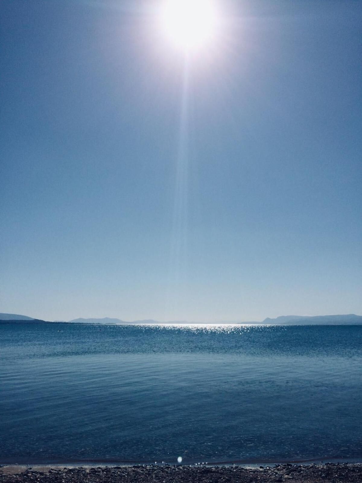 Cielo despejado sobre un mar tranquilo con una costa lejana.